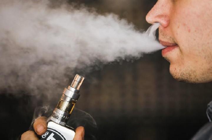 Seorang pria merokok vaporizer elektronik, juga dikenal sebagai e-cigarette atau vape